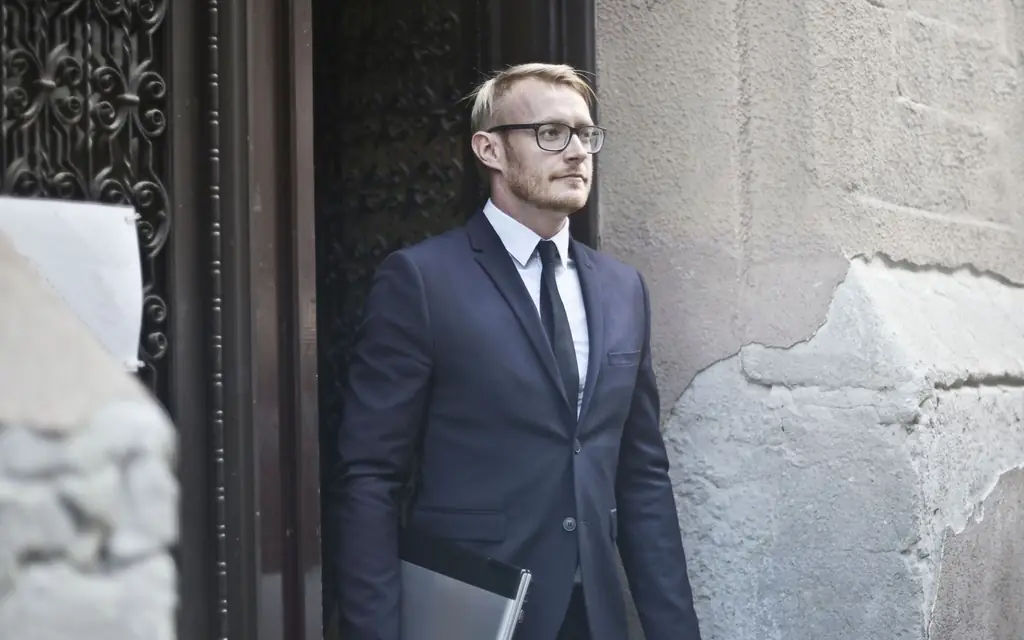 Chauffeur in a dark suit waiting at a doorway